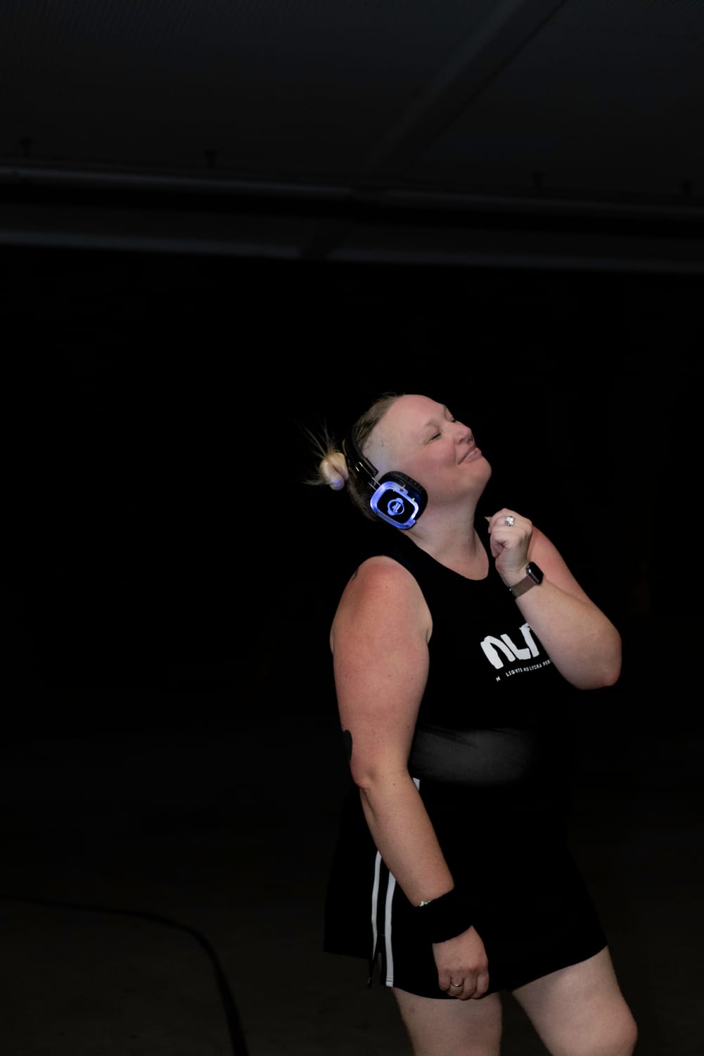 Image from tenth birthday, dance commander bryony is on stage in front of an LED NLNL 10 backdrop. her hand is on her heart and she is looking humbled.