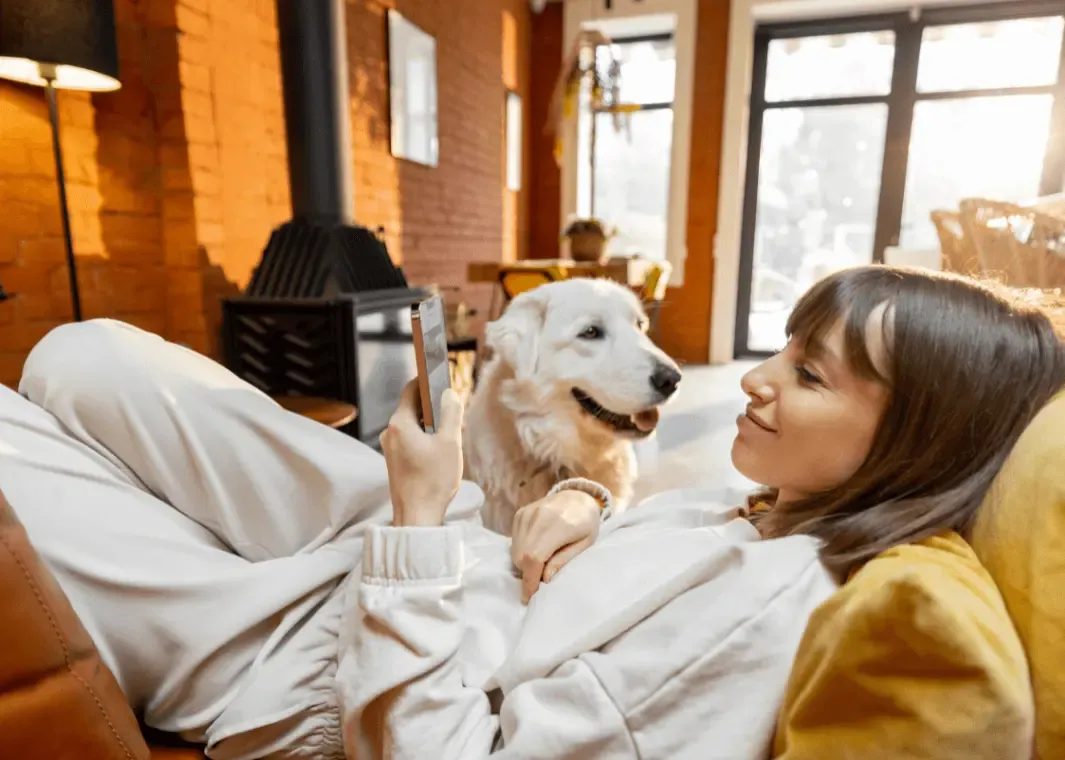 woman owner in the couch with a pet and a watching the phone