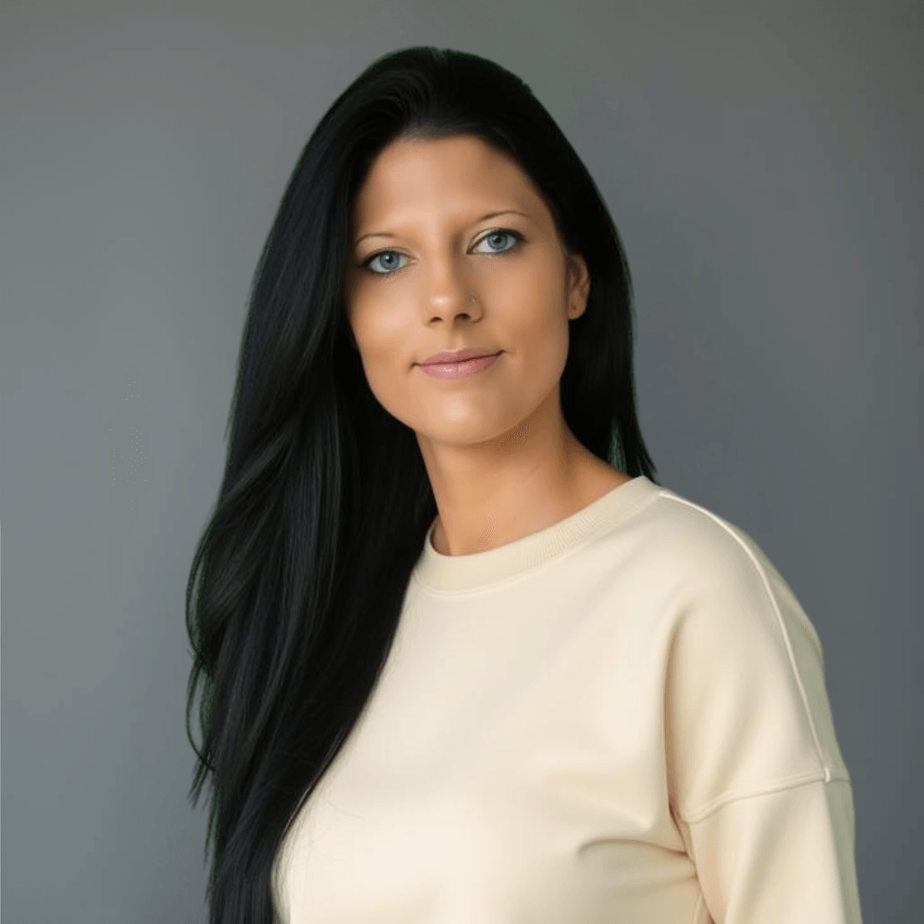 Professionelles Porträt einer Frau mit langen, glatten schwarzen Haaren, die einen cremefarbenen Pullover trägt. Sie hat einen ruhigen und freundlichen Ausdruck, während sie vor einem schlichten grauen Hintergrund posiert. Perfekt für Business-,Coaching- oder Lifestyle-Webseiten.