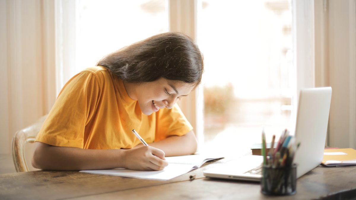 Une étudiante souriante travaille son cahier