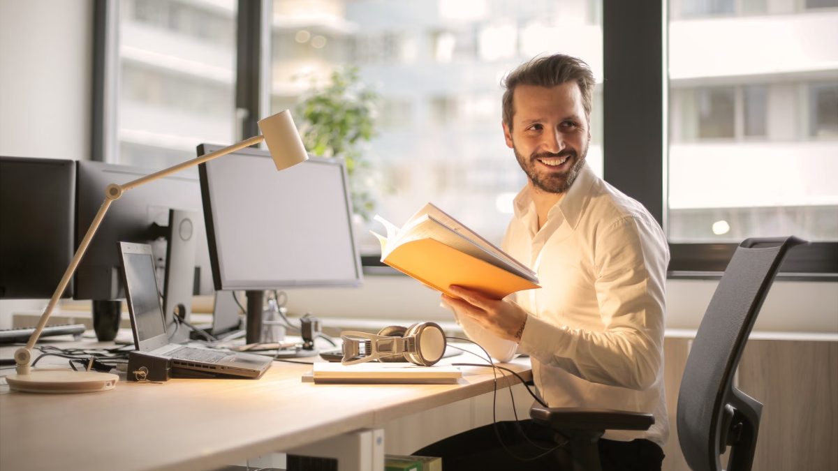 Un homme souriant lit un livre