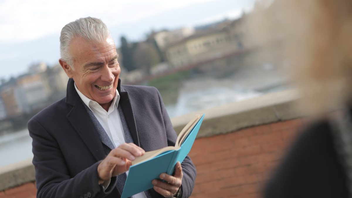 Un homme souriant lit un livre