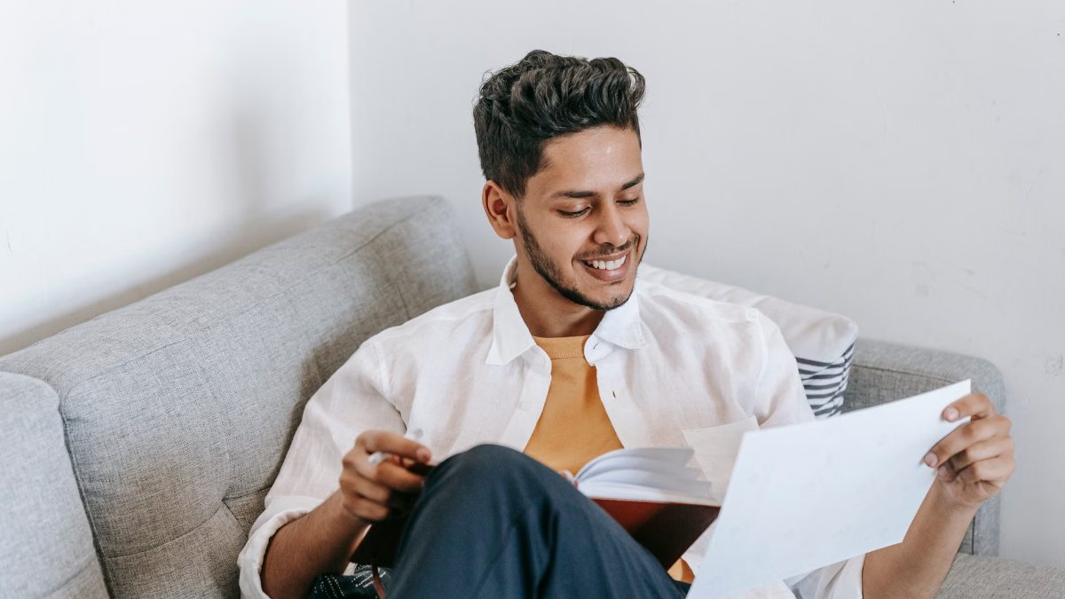 Un homme souriant lit un livre