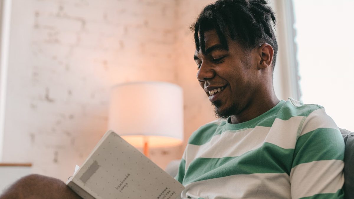 Un homme souriant lit un livre