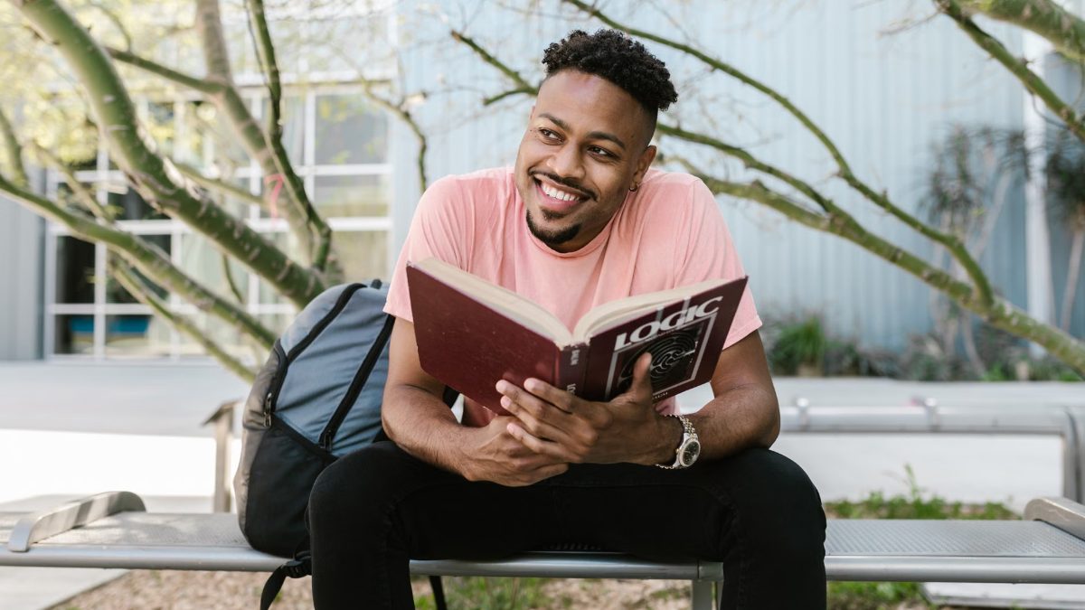 Un homme souriant lit un livre
