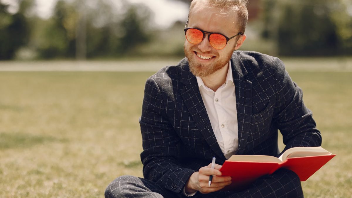 Un homme souriant lit un livre