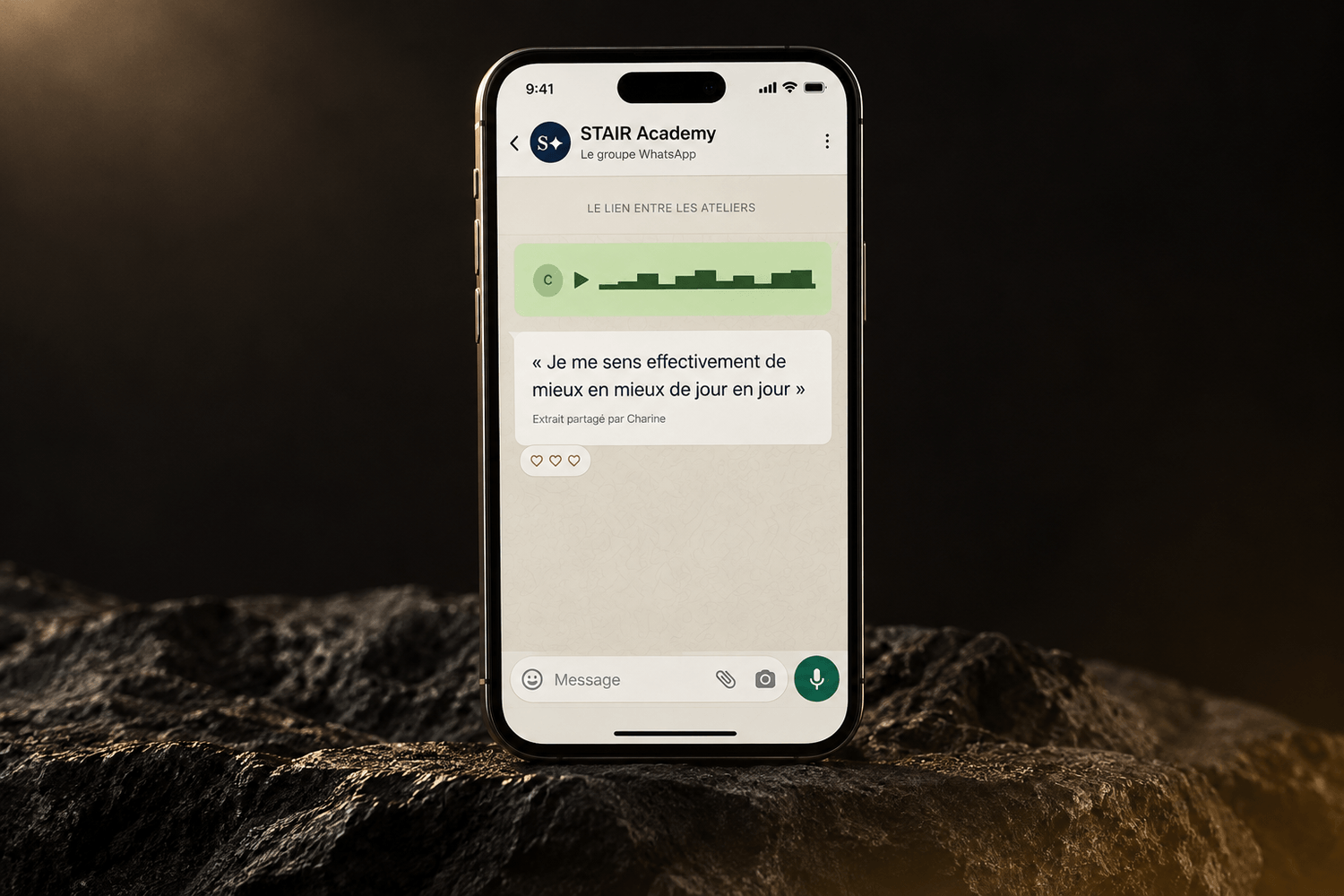 Présentation du groupe WhatsApp privé STAIR Academy sur un téléphone posé sur une pierre sombre. Le retour affiché est : Je me sens effectivement de mieux en mieux de jour en jour.