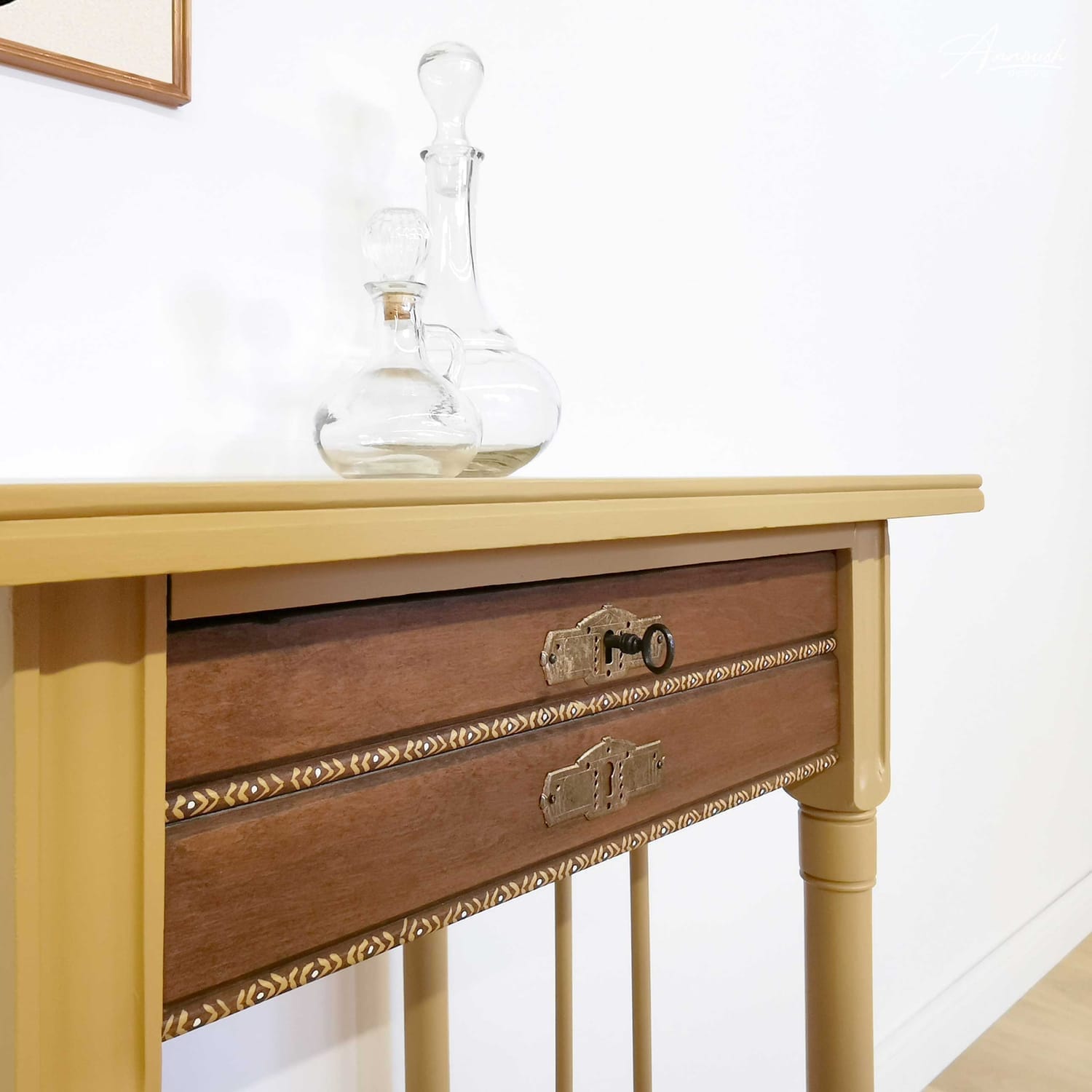 Detailansicht auf die seitliche Front eines Boho Beistelltischs, das im Farbton "Golden Hour", einem gedeckten wunderschönen Goldgelbton, gestrichen wurde. Dekoriert ist die Oberfläche mit zwei Glaskaraffen.