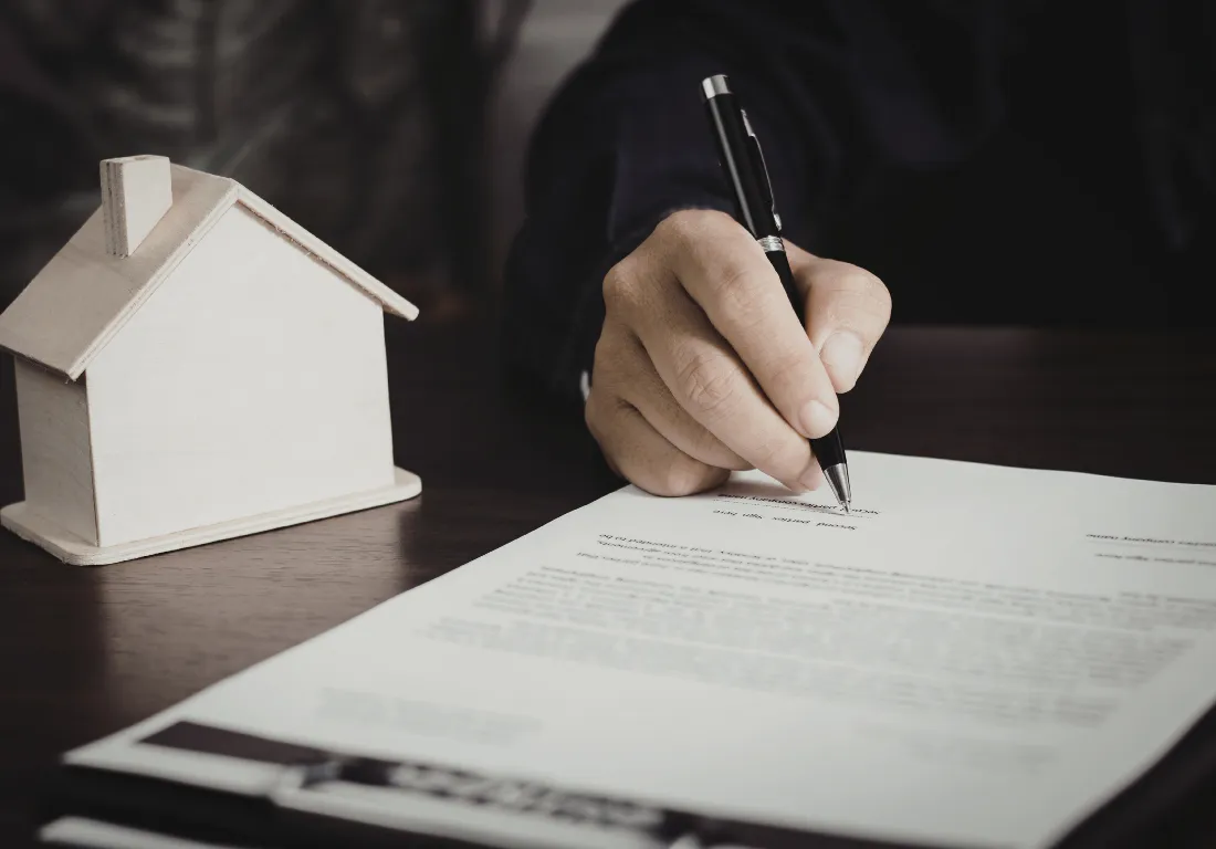 Pessoa a analisar documentos imobiliários, como a Caderneta Predial e a Certidão de Registo.