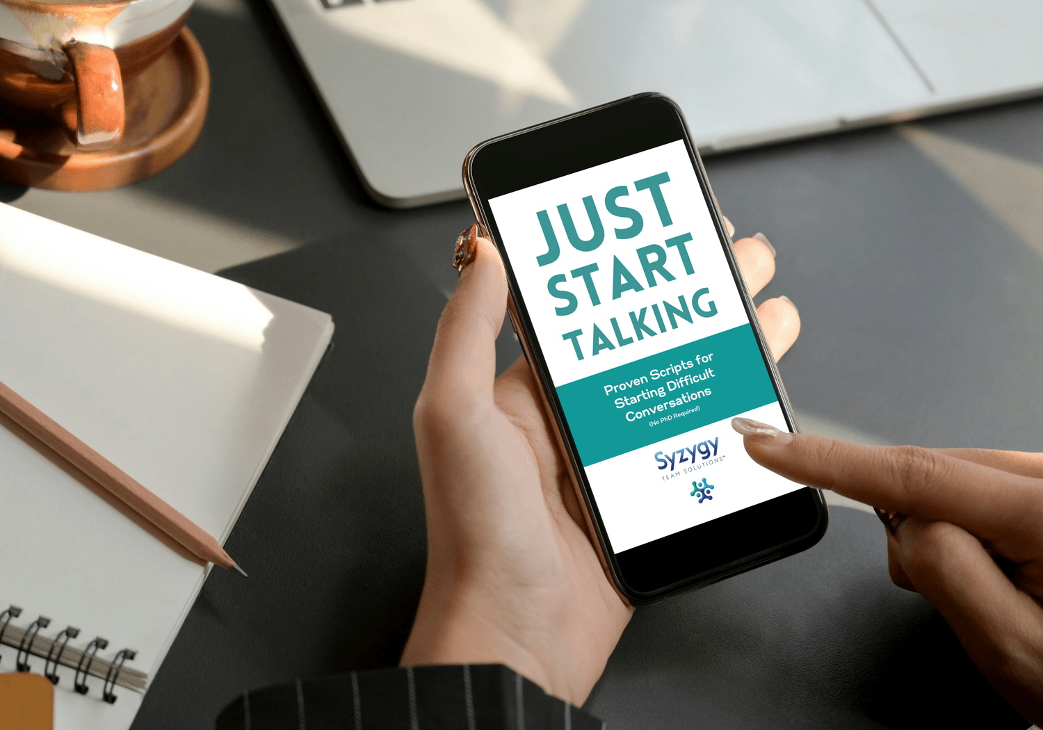 Laptop computer on a light wood desk with a notepad and pens nearby. Laptop screen showing title page of Toolkit - Anxiety-to-Action Toolkit: Transform your fears into energy and action - today!