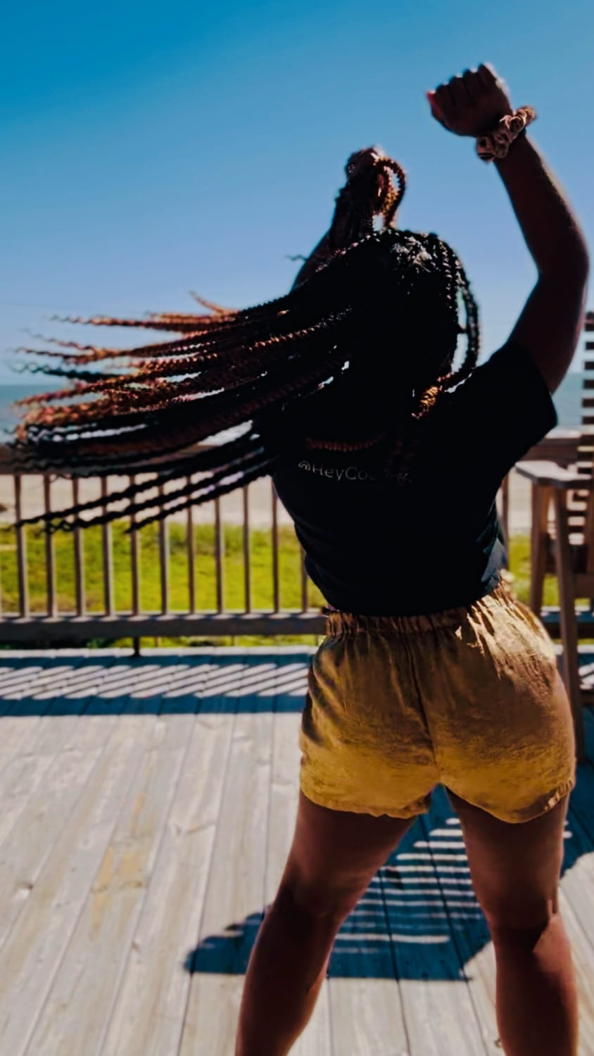 Kala C. Simmons, MSW | Confidence & Authenticity Coach, Visionary Founder & CEO of The Kollective dancing with arms stretched toward the sky