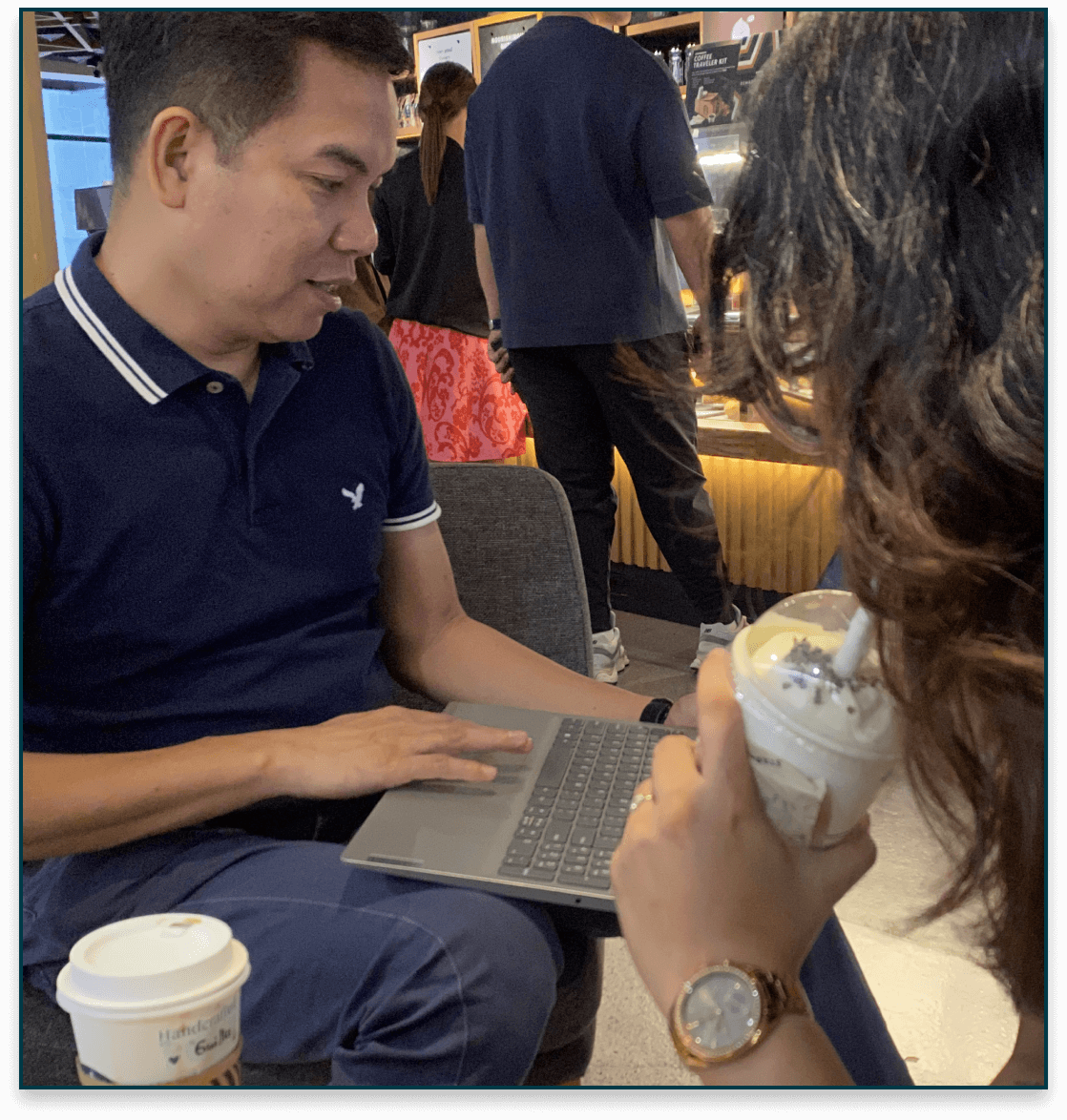 Advisor discussing a plan on a laptop with a client at a café; coffee cups on the table.