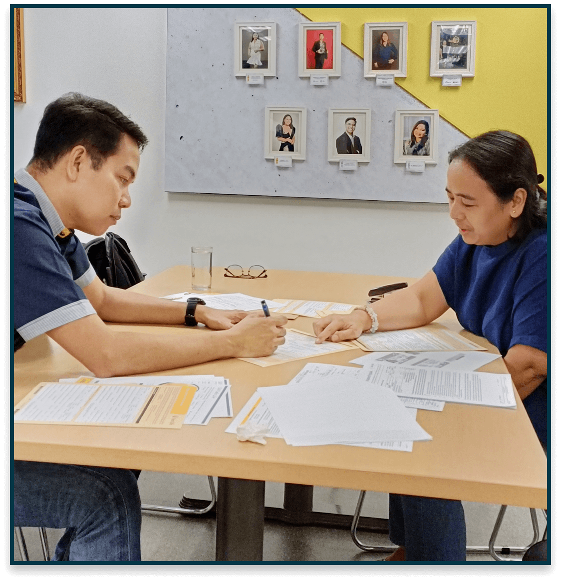 Advisor and client reviewing protection plan documents at an office table with forms and pen.