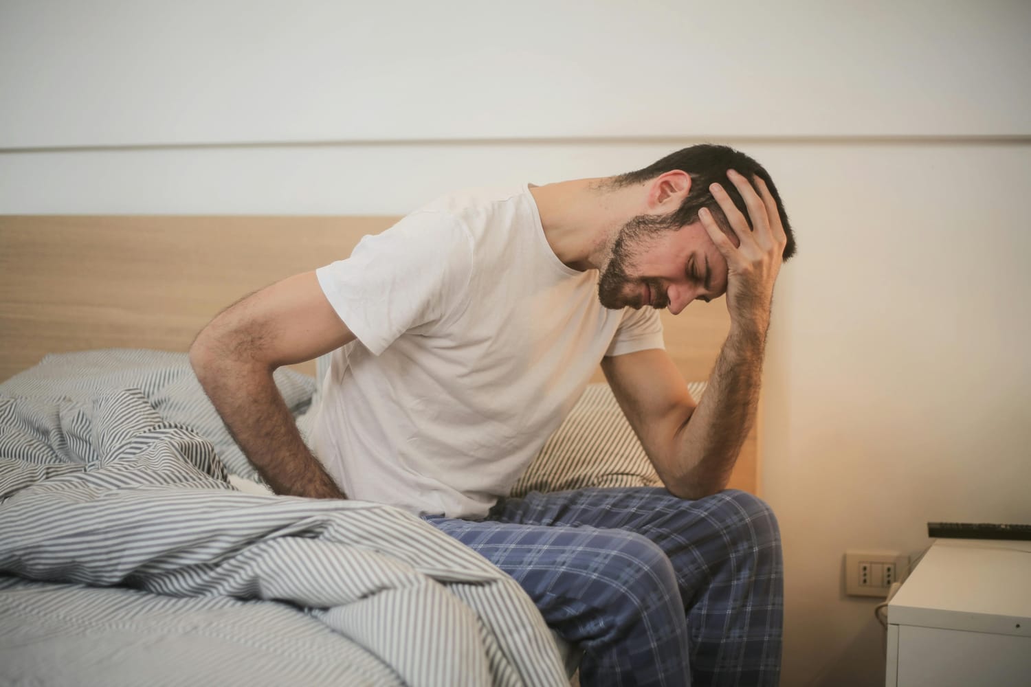 Photo d'un homme en pyjama ayant de la difficulté à se lever de son lit