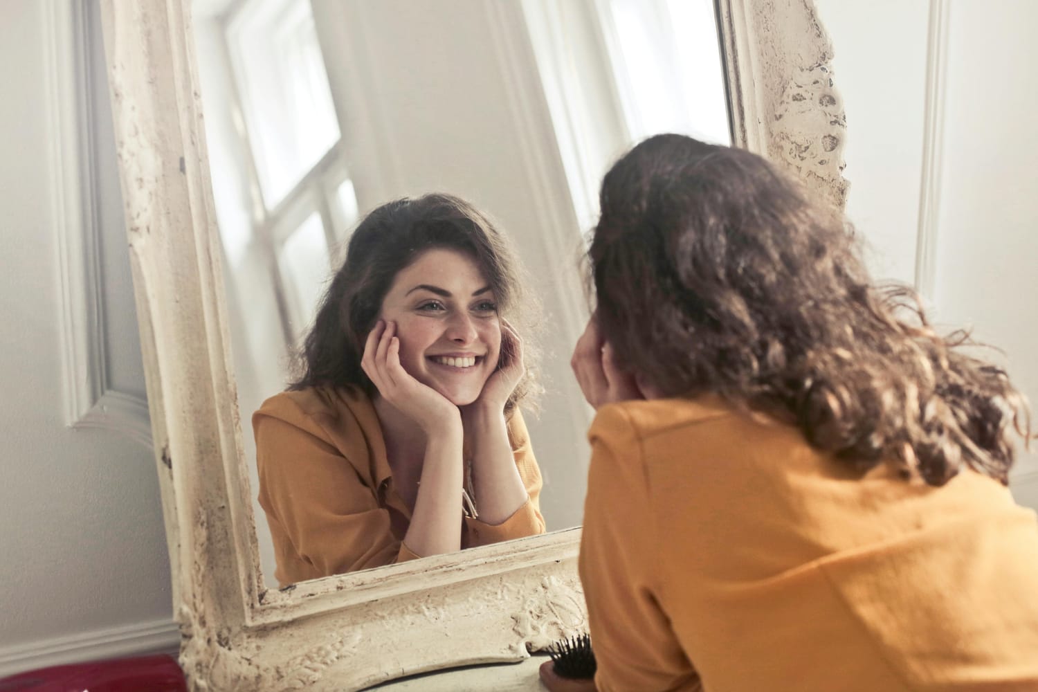 Photo d'une femme qui se regarde dans le miroir en souriant 