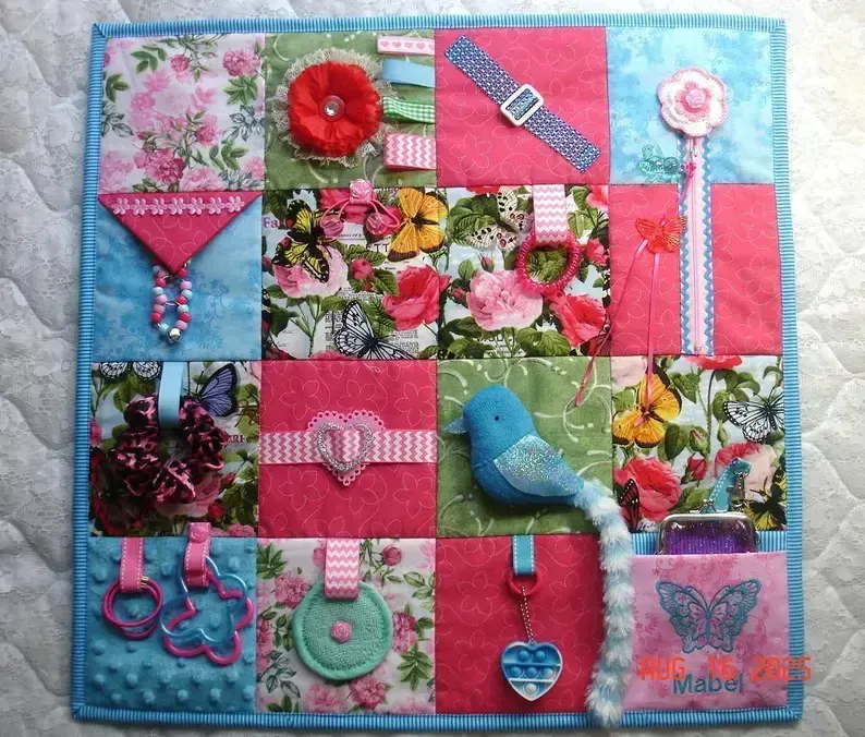 Fidget activity sensory quilt blanket with bluebird, red and pink roses, and butterfly designs, offering tactile stimulation for dementia patients.