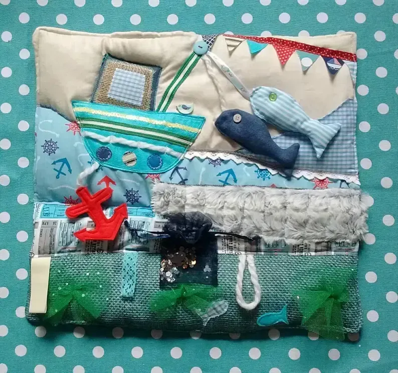 Dementia fidget blanket with beach and fishing boat theme, designed with tactile activities to calm restlessness and engage the hands.