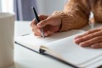 Une main qui écrit dans un carnet ouvert